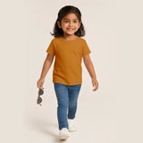 Child wearing a Supima cotton t-shirt and blue jeans, holding sunglasses, on a plain background