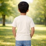 Child standing in a park wearing suvin gold cotton with trees and grass in the background