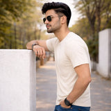 Man wearing Suvin gold cotton off-white white t-shirt leaning against a wall outdoors.