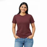 Woman wearing a maroon Suvin gold cotton t-shirt and blue jeans on a white background