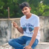 Man wearing a 'California' t-shirt sitting outdoors with greenery in the background