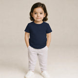 Child wearing a Suvin Gold Cotton navy blue t-shirt and light gray pants on a beige background
