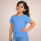 Young girl wearing a suvin gold cotton blue t-shirt and jeans against a plain background