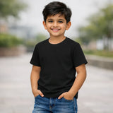 Child wearing a black t-shirt and blue jeans standing outdoors with a blurred background
