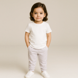 Child wearing a 100% Suivn Gold Cotton white t-shirt and light gray pants against a beige background