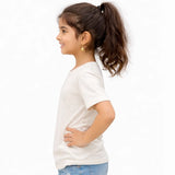Young girl wearing a off white suvin gold cotton t-shirt and blue jeans on a white background