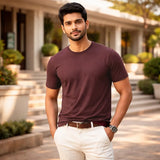 Man wearing a maroon suvin gold cotton t-shirt and white pants standing outdoors 